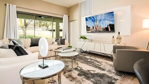A modern living room with a sofa, coffee table, and a large TV mounted on the wall.