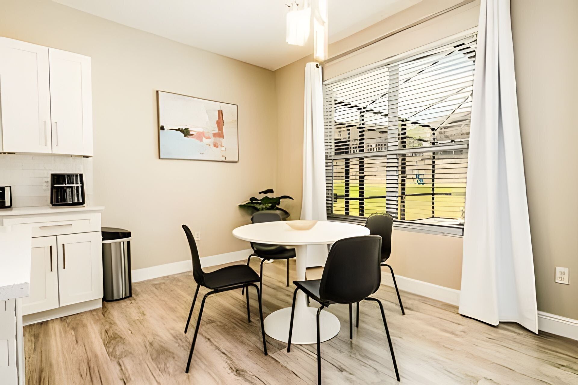 A modern kitchen with white cabinets, a round dining table, and black chairs.