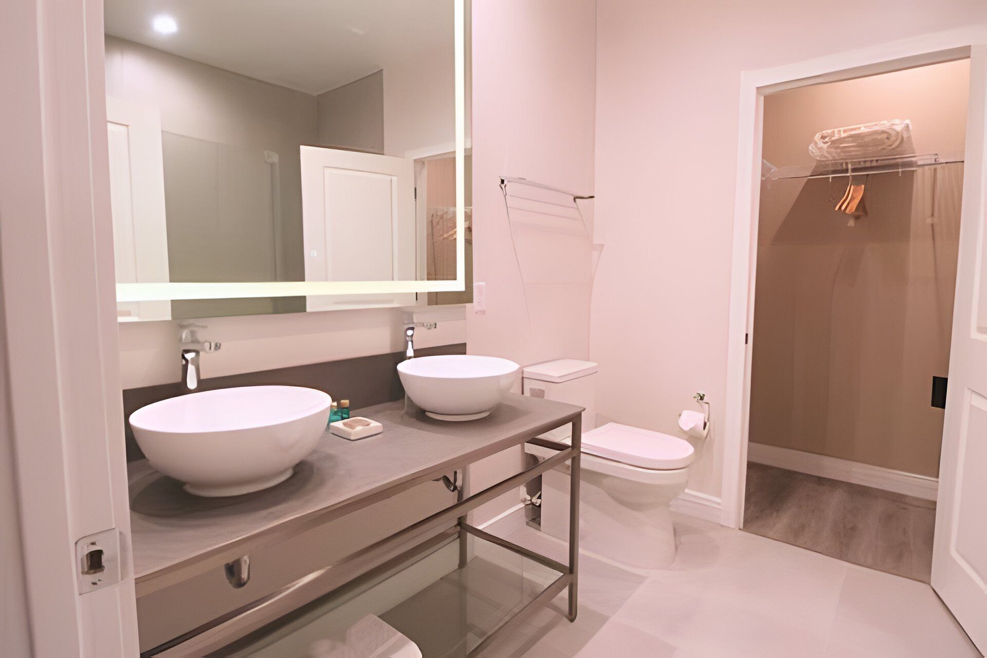 A modern bathroom with two sinks, a toilet, and a shower area.