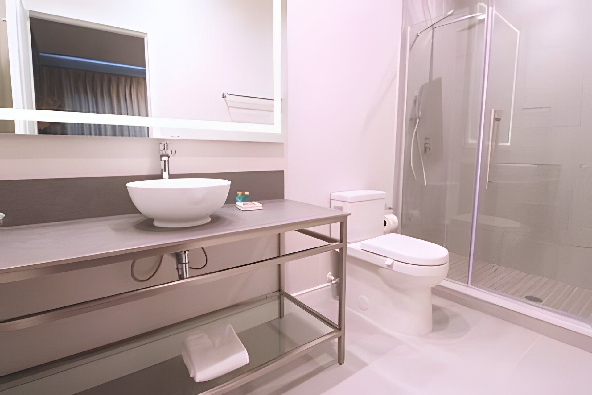 A modern bathroom with a white sink, toilet, and glass shower enclosure.
