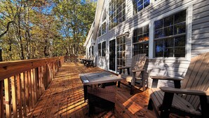 A wooden deck with a table and chairs, overlooking a forested area. - Chickadee Retreat - Creekside Pocono Forest, fireplace, games, pool, lakes (Albrightsville)