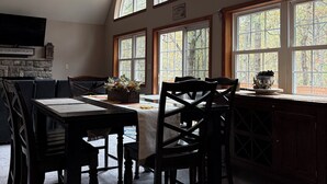 A dining area with a high ceiling, large windows, and a ceiling fan. - Chickadee Retreat - Creekside Pocono Forest, fireplace, games, pool, lakes (Albrightsville)