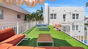 A rooftop patio with artificial grass, a striped canopy, and outdoor furniture. - #10 Unit in Mid-century Art-Déco Building KingBed EnSuiteBath Steps>Beach PetsOK (Miami Beach)