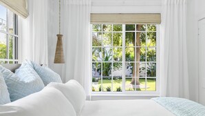 A bedroom with a large window, white bedding, and a hanging light fixture. - FlipFlopsOn III • 1/2 Mile to Siesta Key • FL’s Gulf Coast • Sarasota (Sarasota)