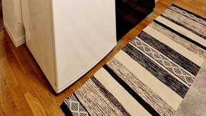 Una cocina compacta con armarios blancos, horno integrado, microondas y hervidor.