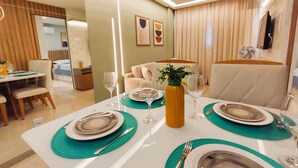 A modern dining area with a table set for four, including plates, cutlery, and glasses. - Rio Park Ave -by TRH Home Stay (Jaboatão dos Guararapes)