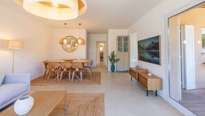A modern living room with a dining area, a sofa, a coffee table, and a large window with a view.