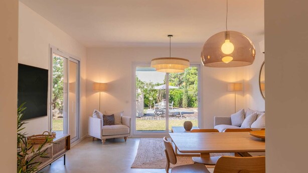 A modern interior with a dining area, a sofa, and a large window.