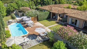 A residential property with a swimming pool, outdoor seating area, and a covered patio.