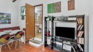 A living room with a fireplace, a bookshelf, a dining area with a table and chairs, and a door leading to another room.