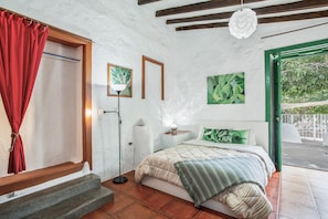 Une chambre à coucher avec un lit, une table de chevet, une lampe et une fenêtre avec un rideau.