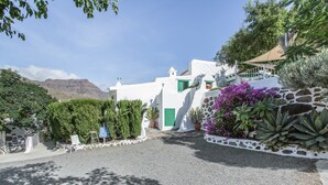 A white building with green accents, a gravel path, and surrounding greenery.