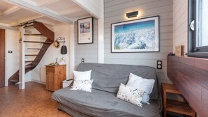 A modern interior with a grey sofa, wooden cabinet, and a staircase.
