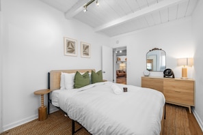 Une chambre à coucher avec un lit, une commode en bois, un miroir et une table de chevet.