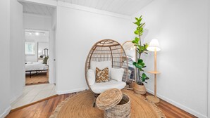 Et værelse med en hvid stol, gulvlampe og en stor plante.