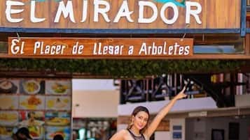 Un letrero de madera para un hotel y restaurante llamado 'EL MIRADOR', con un diseño de palmera y ola.