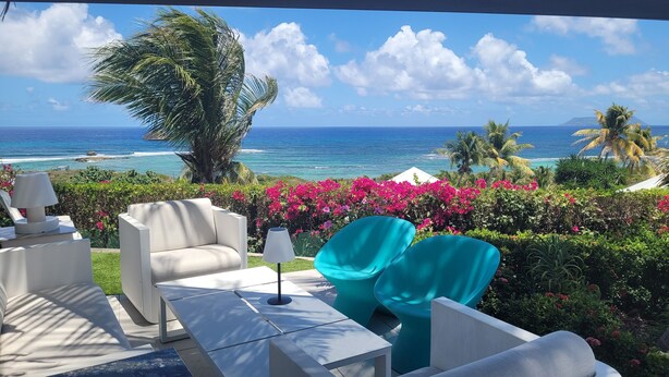 A terrace with white furniture, a view of the ocean, and pink bougainvillea flowers. - Villa AMAYA for 4 people (Saint-François)