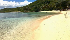 A beach with clear water, sandy shore, and a hill with vegetation. - Villa AMAYA for 4 people (Saint-François)