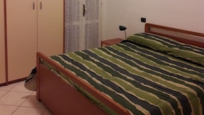 Ένα υπνοδωμάτιο με ένα κρεβάτι, μια ντουλάπα και ένα παράθυρο με κουρτίνες.