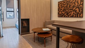 A modern living room with a wooden floor, a sofa, a coffee table, and a wall-mounted abstract art piece. - Sosuite 1bed Apt w Roof Deck, Gym, Laundry (Philadelphia)
