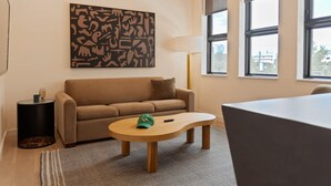 Ett modernt vardagsrum med en soffa, ett soffbord, en lampa och en stor, abstrakt tavla på väggen.