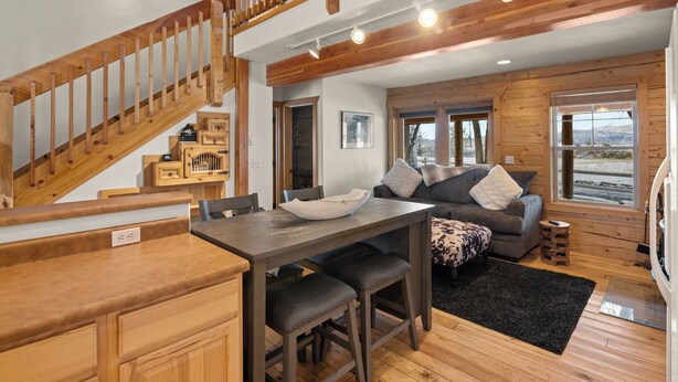A spacious living area with a wooden staircase, a dining table with bar stools, and a cozy seating area with a sofa and cushions. - Charming Cabin in Beautiful Park-Like Setting (Silt)
