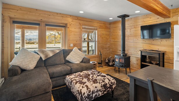 A cozy living room with a sofa, ottoman, and a fireplace.