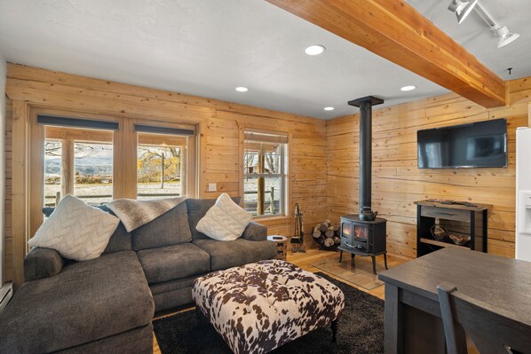 A cozy living room with a sofa, ottoman, and a fireplace.
