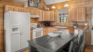 A kitchen with wooden cabinets, a white refrigerator, a stove, and a sink. - Charming Cabin in Beautiful Park-Like Setting (Silt)