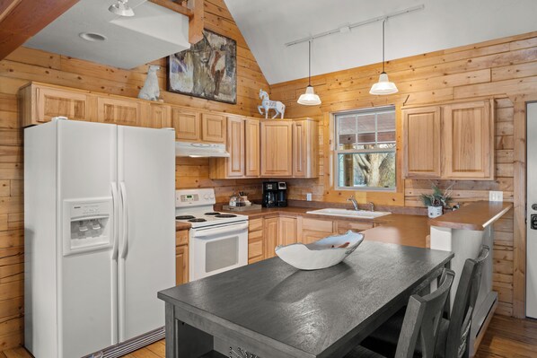 A kitchen with wooden cabinets, a white refrigerator, a stove, and a sink. - Charming Cabin in Beautiful Park-Like Setting (Silt)