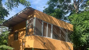 En toetages bygning med gul facade, en overdækket veranda og en trappe op til øvre etage.