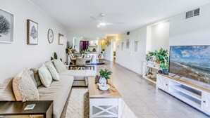 A modern living room with a sofa, coffee table, TV, and artwork on the walls. - Pavillions  Ocean Breeze Apartment 119 (Agnes Water)