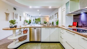 Una cocina moderna con armarios blancos, encimeras de granito y electrodomésticos de acero inoxidable.
