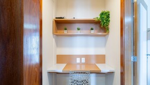 Un espace de travail compact comprenant un bureau en bois, une chaise blanche et une étagère avec des plantes.