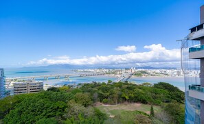A coastal cityscape with a bridge, dense greenery, and modern buildings. - Fully Equipped Accommodations in a Building With Pool and gym in Downtown Florianopolis - Lins (Florianópolis)