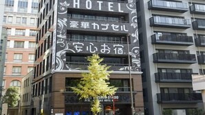 A multi-story building with a sign for a 'LUXURY CAPSULE HOTEL' and Japanese text.