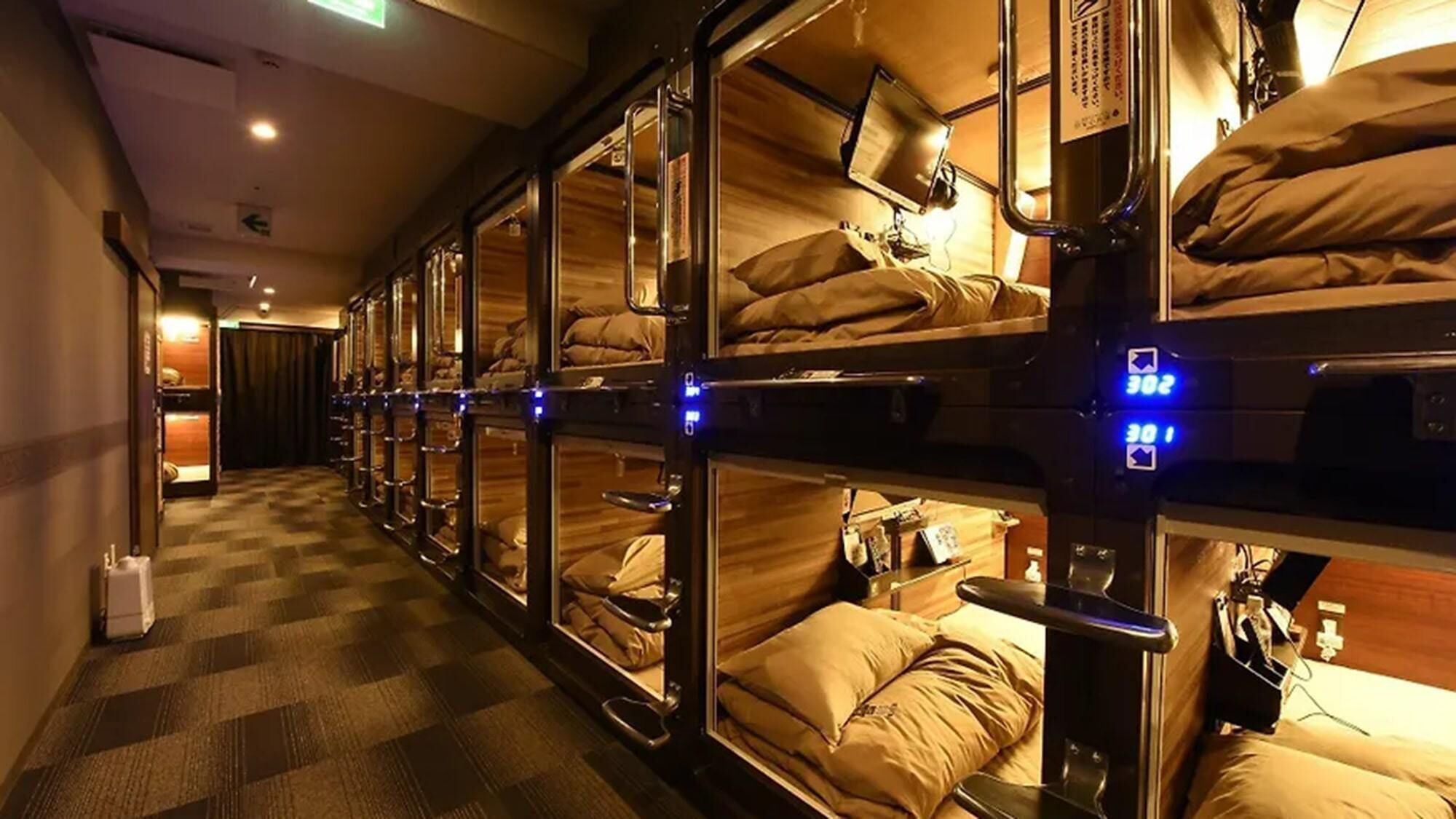 Une rangée de lits superposés, chacun doté d’une tête de lit, d’une petite table et d’un oreiller.