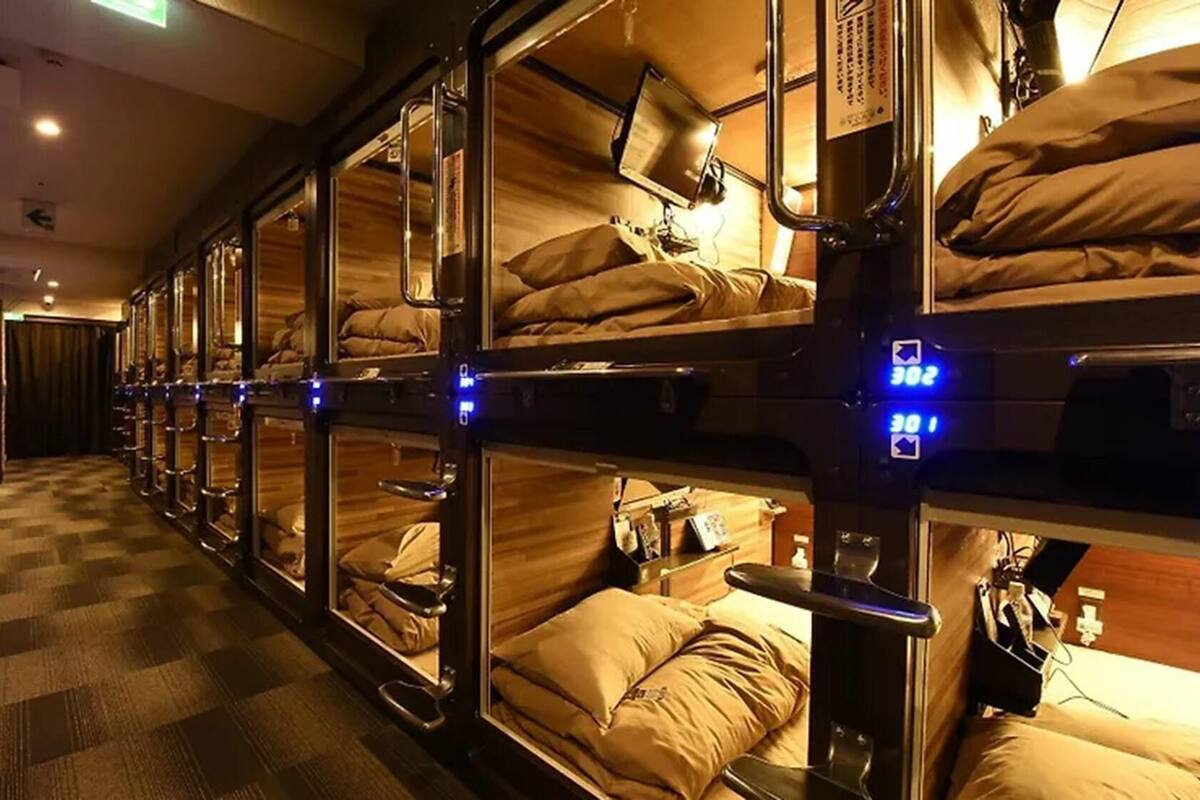Une rangée de lits superposés, chacun doté d’une tête de lit, d’une petite table et d’un oreiller.