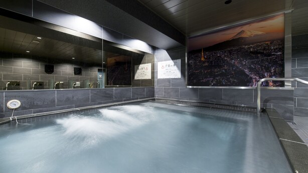 A swimming pool with a cityscape mural, tiled walls, and a clock.