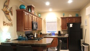 Una cocina con armarios de madera, un refrigerador negro y una isla central con sillas.