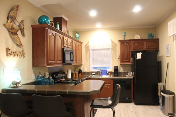 A kitchen with wooden cabinets, a black refrigerator, and a central island with chairs.