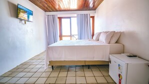 Une chambre avec un lit, un petit réfrigérateur et une fenêtre avec des rideaux.