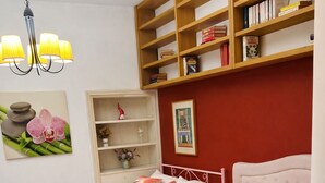 Quarto com duas camas, uma estante de livros e um quadro na parede.