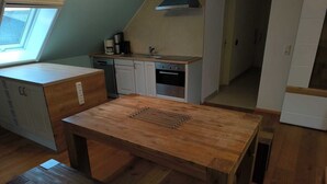 A compact kitchen with a wooden table and bench, a window, and a built-in oven. - 3-bedroom apartment for 6-8 persons near Munich, Augsburg (Merching)