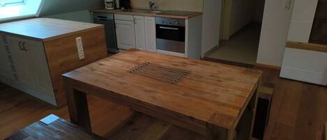 A compact kitchen with a wooden table and bench, a window, and a built-in oven.