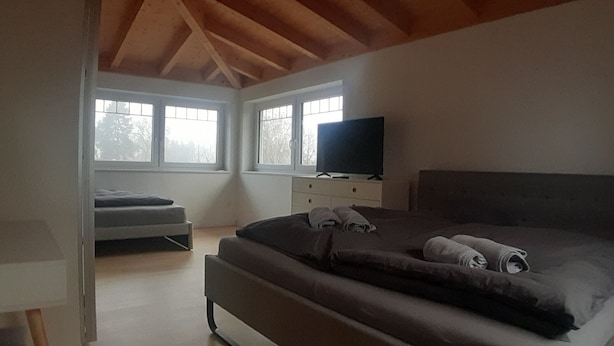 A bedroom with a bed, a TV, a desk, and a window. - 3-bedroom apartment for 6-8 persons near Munich, Augsburg (Merching)