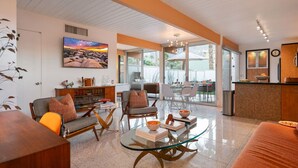 A spacious living area with a glass coffee table, comfortable seating, and a large painting on the wall. - Ocotillo mid-century lux pad with oversized patio (Palm Springs)