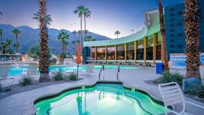 A pool area with lounge chairs, palm trees, and a building with large windows. - Ocotillo mid-century lux pad with oversized patio (Palm Springs)