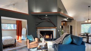 A spacious living room with a fireplace, a sofa, a chair, and a bed.