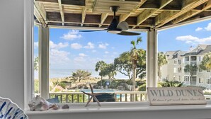 A view from a window with a ceiling fan, a sign reading "WILD DUNES," and a pool area visible outside. - Port O' Call D203 - Direct Ocean View! Beach! (Isle of Palms)